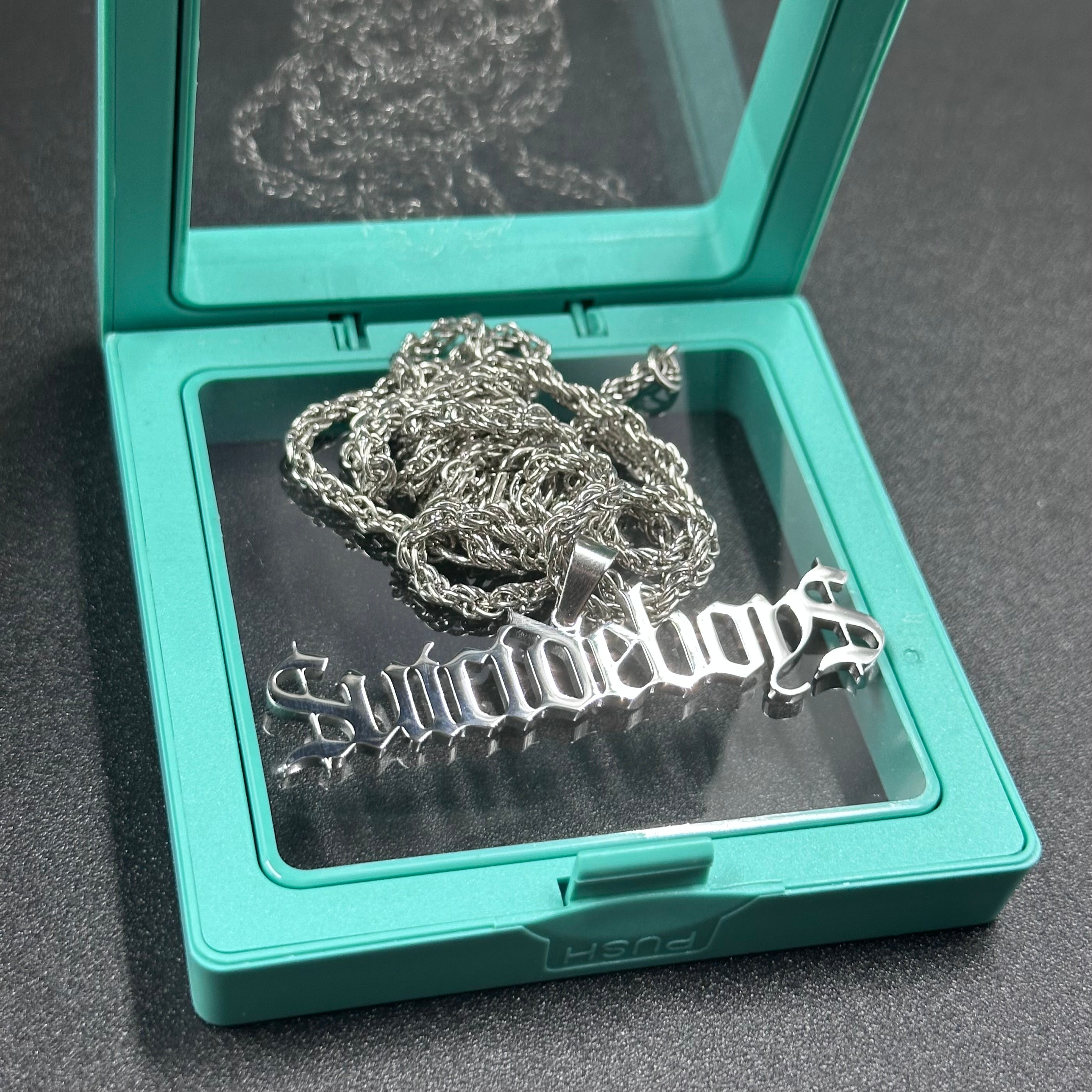 $uicideboy$ wordmark pendant and chain in a green jewelry box