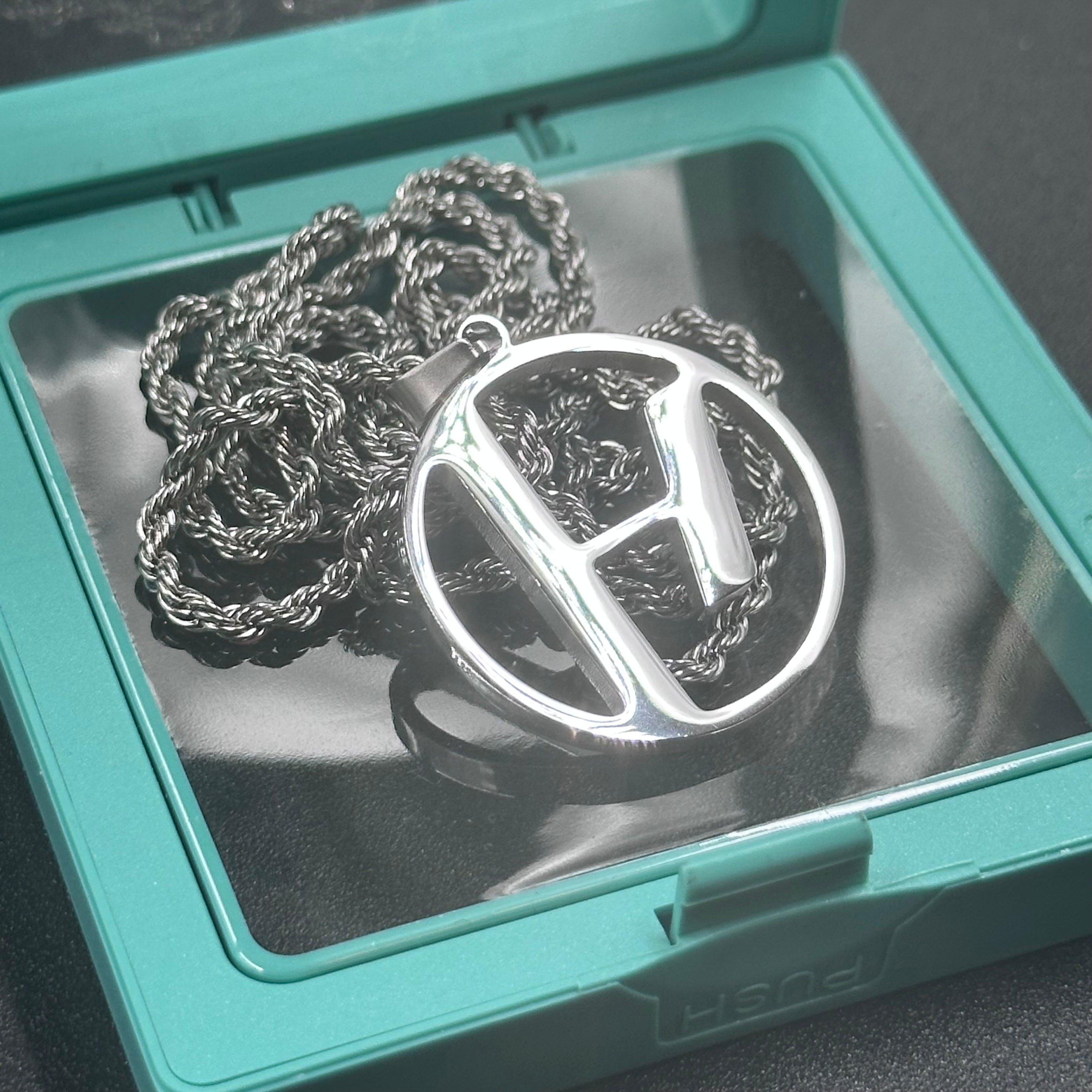 Twenty One Pilots Skeleton Clique pendant and chain in a green jewelry box