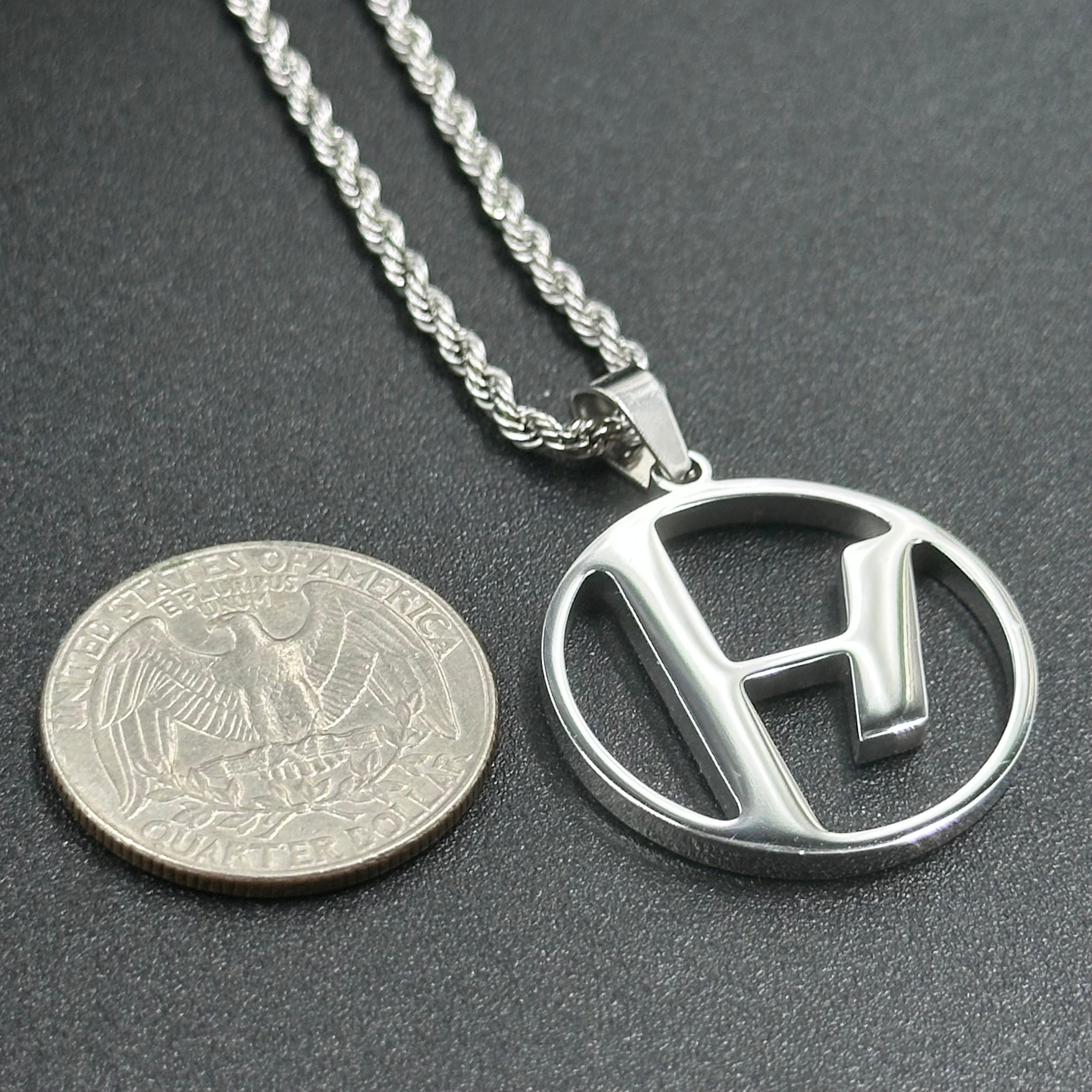 Twenty One Pilots Skeleton Clique pendant beside a US quarter for scale